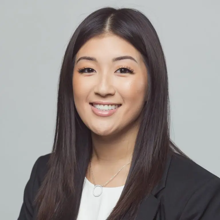 Smiling Asian woman with long straight hair wearing a black suit and white top