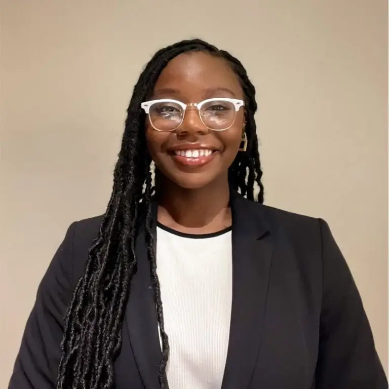 African American woman wearing glasses and a black suit smiling