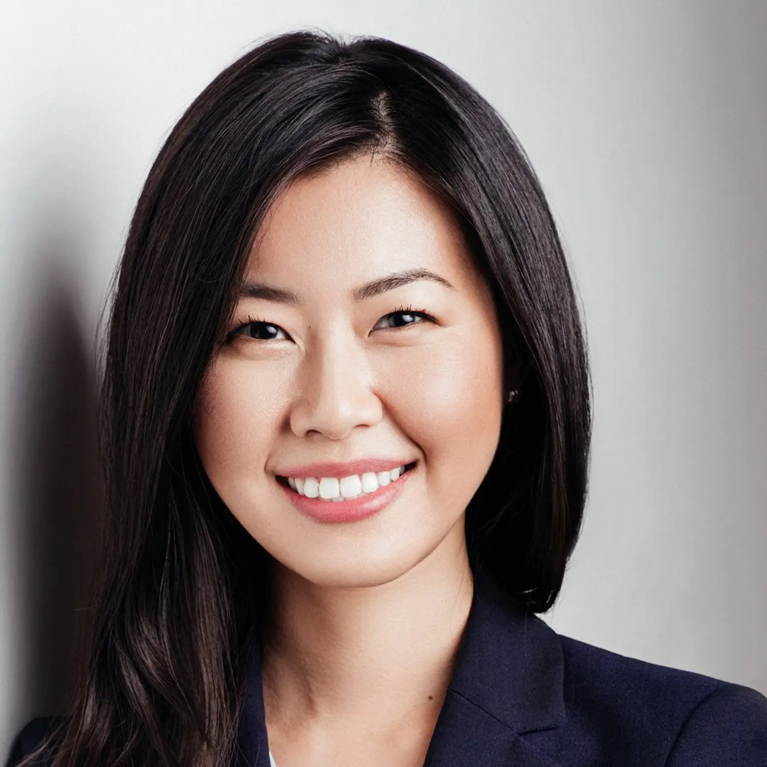 Asian woman with long dark hair, dressed in a dark blazer.