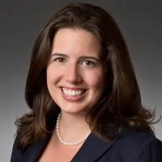 Woman with shoulder length brown hair and pearls smiling.