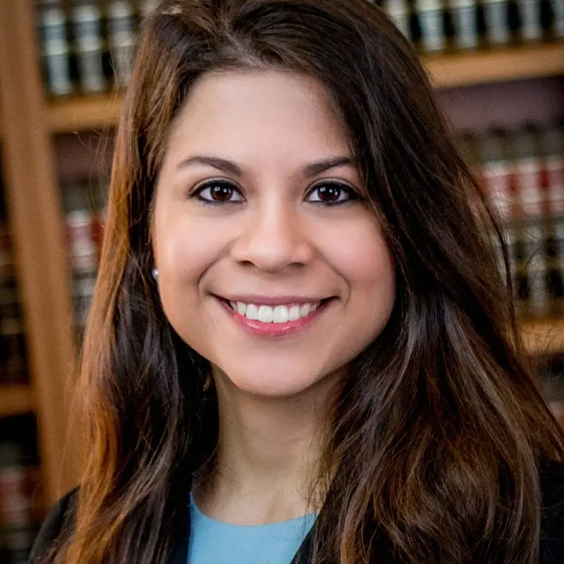 Woman with long brown hair in front of law bookshelf.