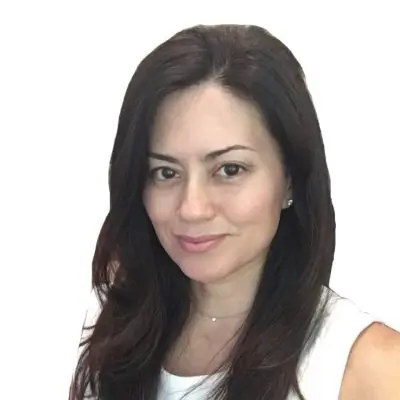 Woman with long brown hair and white top smiling.