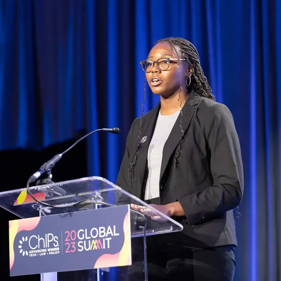 African American woman in front of a podium speaking to a crowd at the ChIPs Global Summit